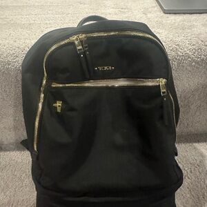 Tumi Black Backpack with Gold Zippers and Smooth Material